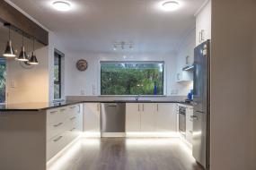 White kitchen, dark benchtop with feature under-cabinet lighting