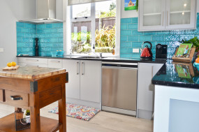 Light grey kitchen with dark stone benchtop and feature tiling